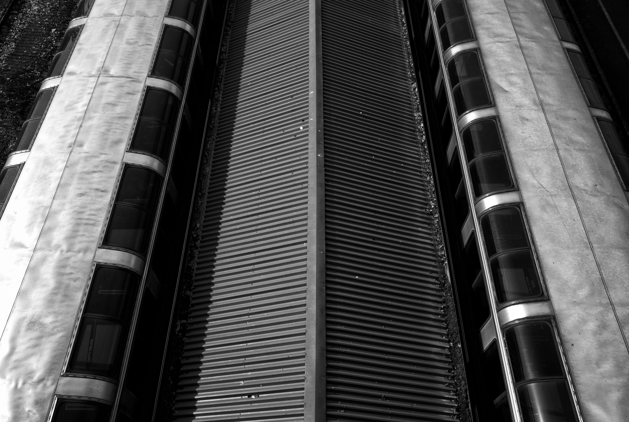 Close-up view of train car exteriors, showcasing sleek metallic surfaces and geometric patterns in high contrast black and white.