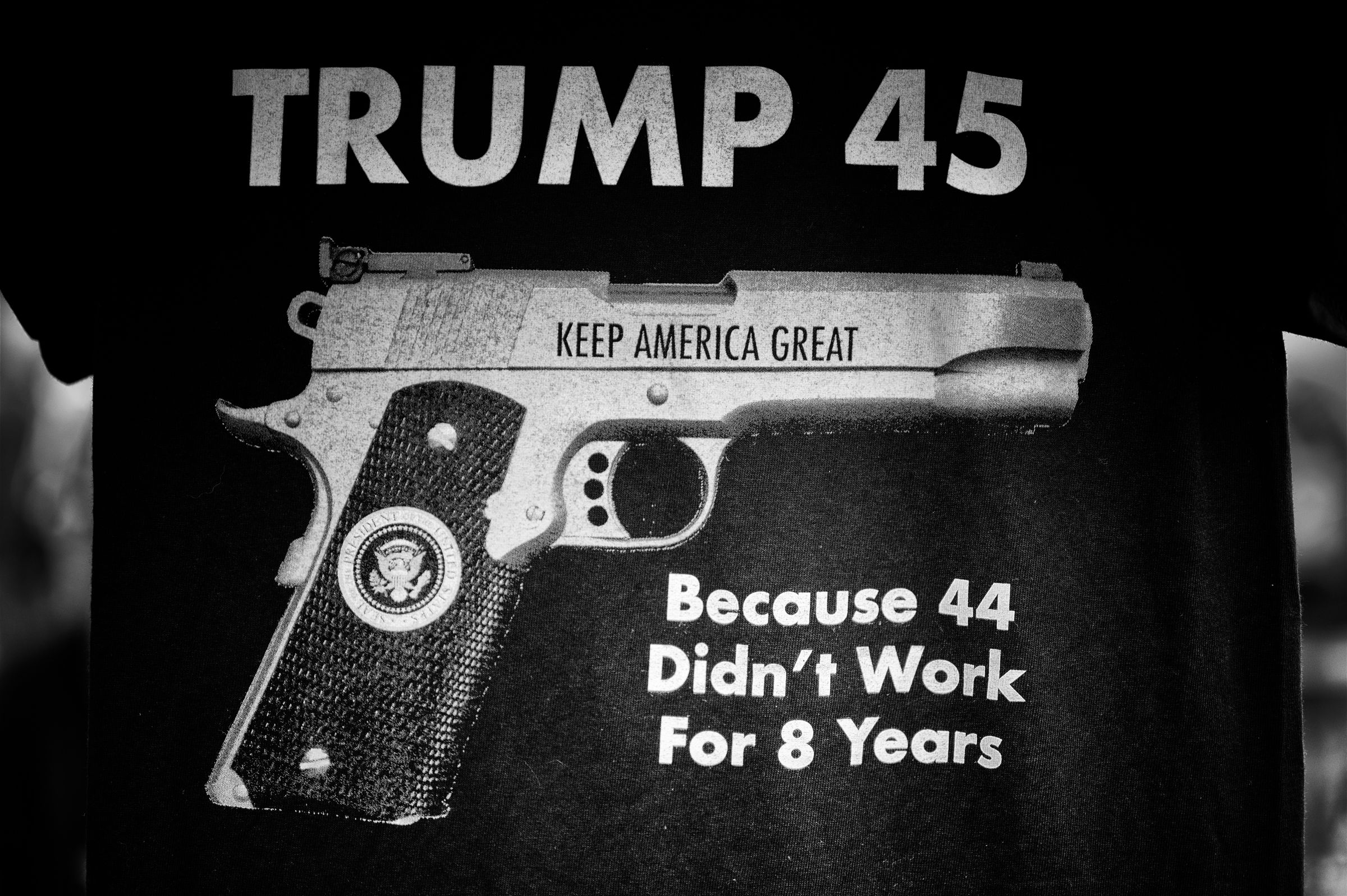 Black t-shirt with the text "TRUMP 45" above an image of a handgun with the words "KEEP AMERICA GREAT" written on the slide and the presidential seal displayed on the grip. Below the handgun the text reads, "Because 44 Didn't Work For 8 Years"