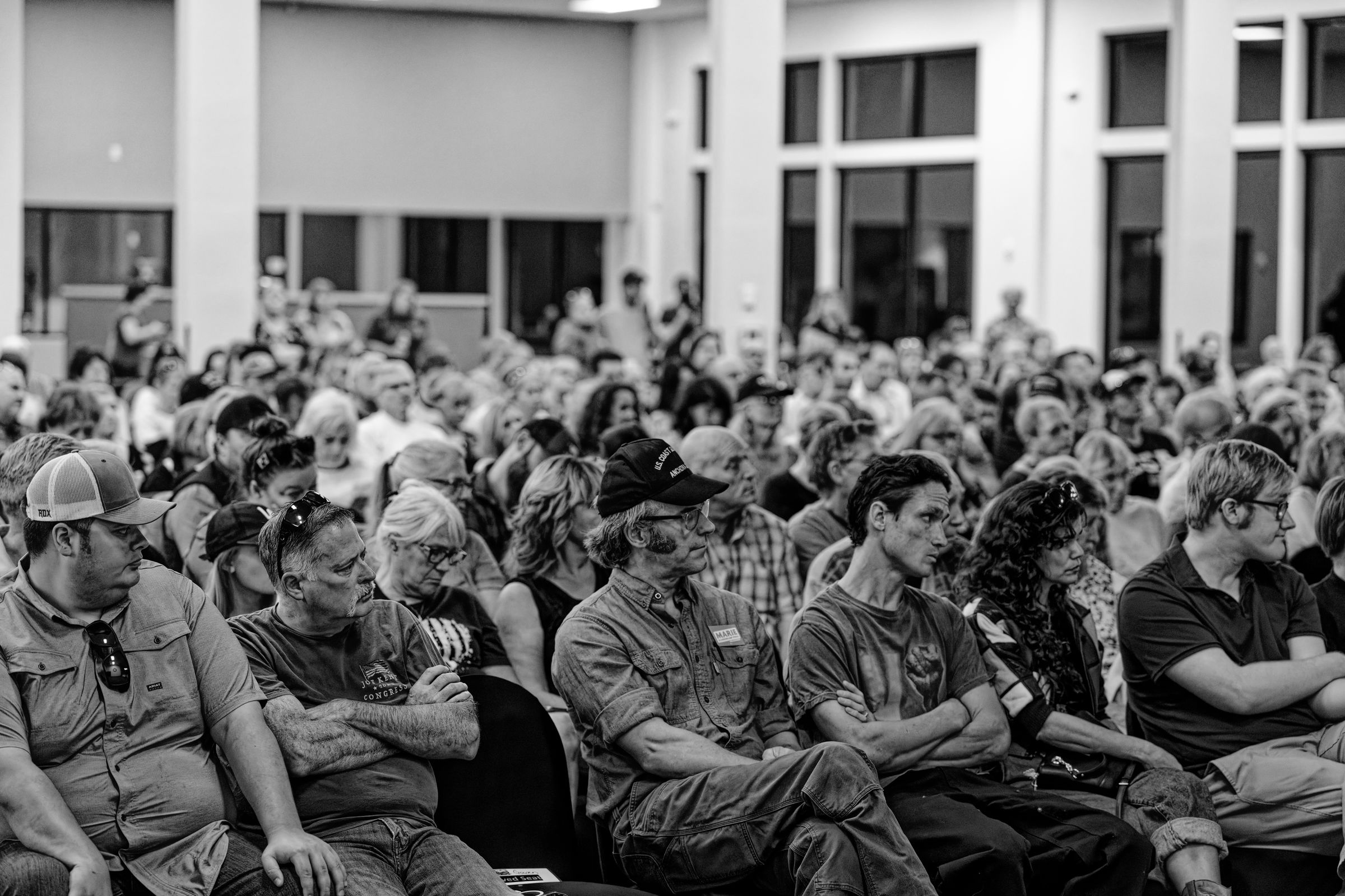 A wide-angle black and white photograph of a large crowd seated in an auditorium.