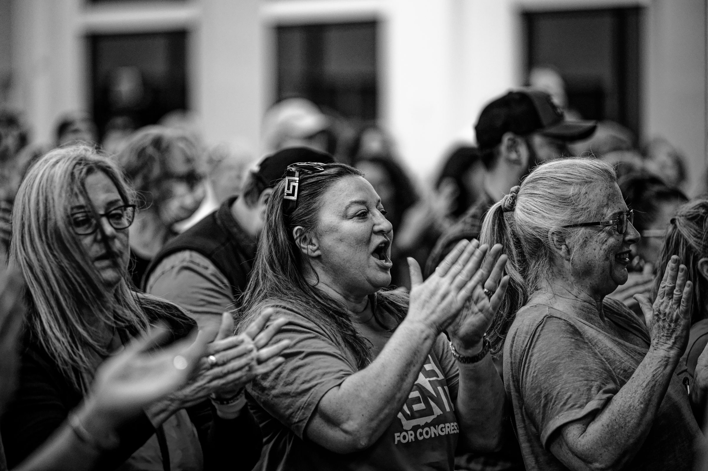 A black and white image of enthusiastic supporters at a political rally, with women in the foreground cheering and clapping energetically.